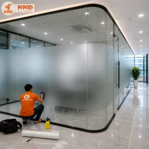 Decal kính mờ trơn được thi công trên vách kính bo góc hiện đại, tăng tính thẩm mỹ và sự chuyên nghiệp cho văn phòng.