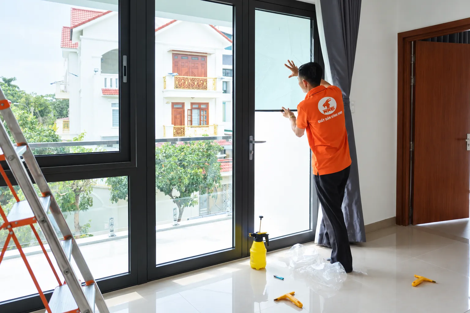 Kỹ thuật viên NND căn chỉnh phim cách nhiệt AP7080 trên ô cửa kính lớn tại biệt thự Vinhomes Riverside Long Biên