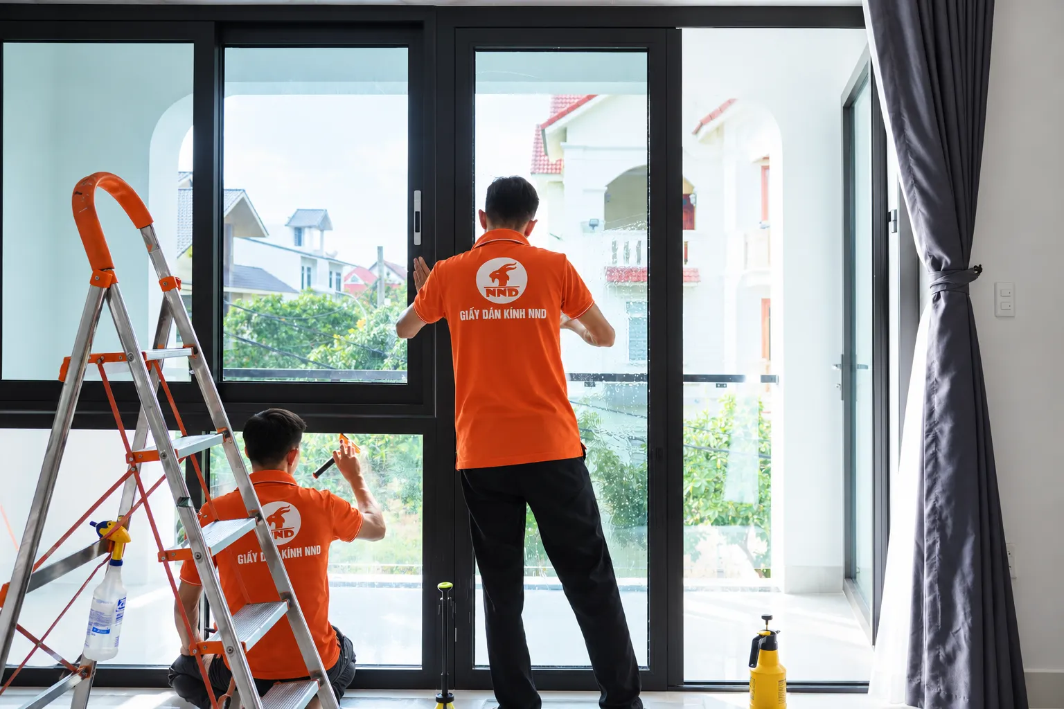 Hai kỹ thuật viên NND thi công phim cách nhiệt AP7080 trên hệ kính lớn tại biệt thự Vinhomes Riverside Long Biên