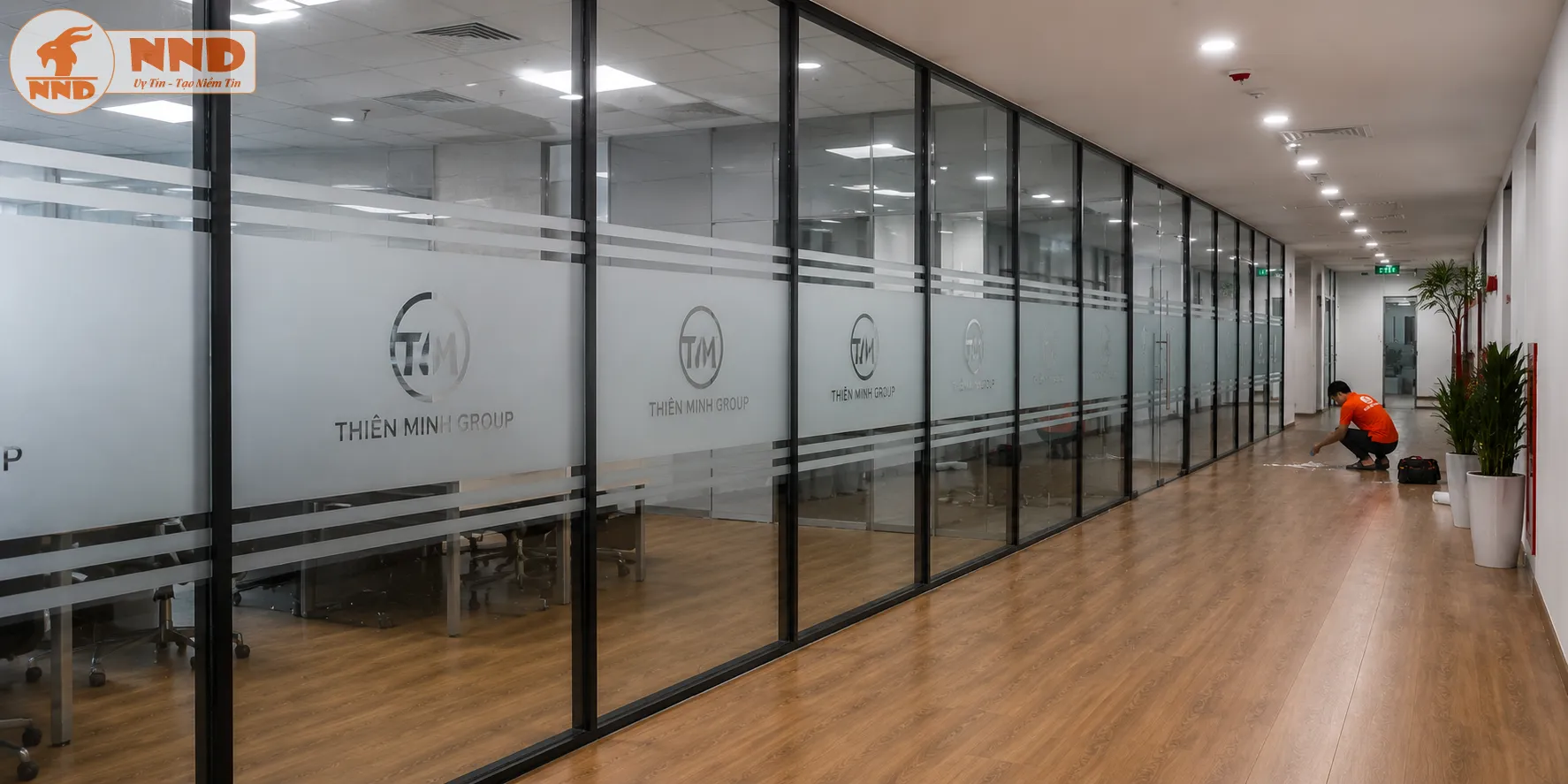 Mẫu decal mờ cắt logo âm bản Thiên Minh Group kết hợp hệ chỉ ngang 3 dòng dán trên dãy vách kính chạy dài, mang lại vẻ đẹp cân đối, sang trọng và tạo chiều sâu rất tốt cho hành lang.