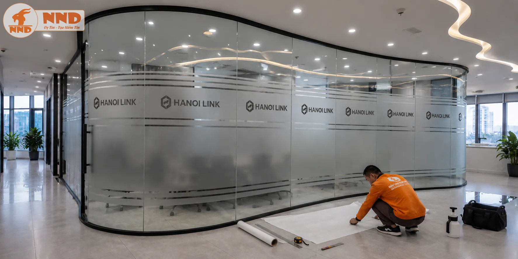 Decal mờ dán kính cắt logo âm bản Hanoi Link lặp lại đồng điệu trên mảng vách kính uốn cong lớn, vừa che chắn tầm nhìn phòng họp khéo léo vừa tạo nên một tổng thể vô cùng bề thế, tinh tế.