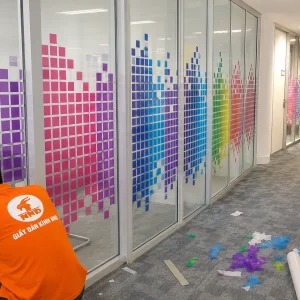 Thiết kế pixel chuyển màu rực rỡ giúp hành lang văn phòng trở nên sinh động và chuyên nghiệp. Decal trong vẫn giữ cảm giác mở, không làm không gian bị bí bách.