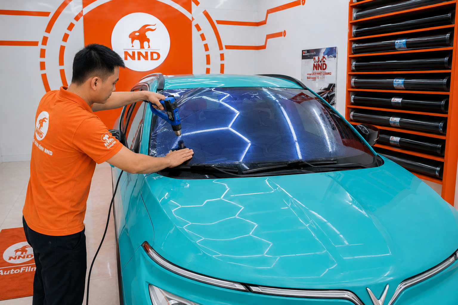 Kỹ thuật viên NND dùng súng nhiệt định hình phim cách nhiệt trên kính lái ô tô trước khi hoàn thiện
