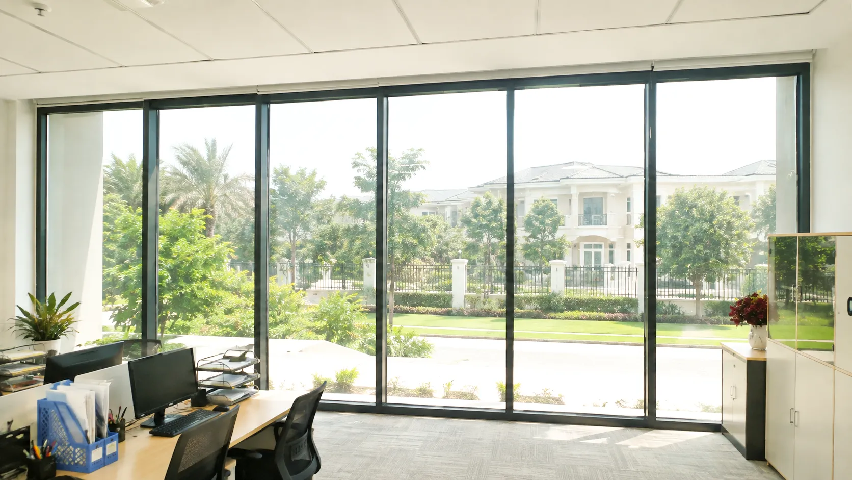 Hệ kính văn phòng lớn trước khi dán phim cách nhiệt, ánh nắng chiếu mạnh vào không gian làm việc.