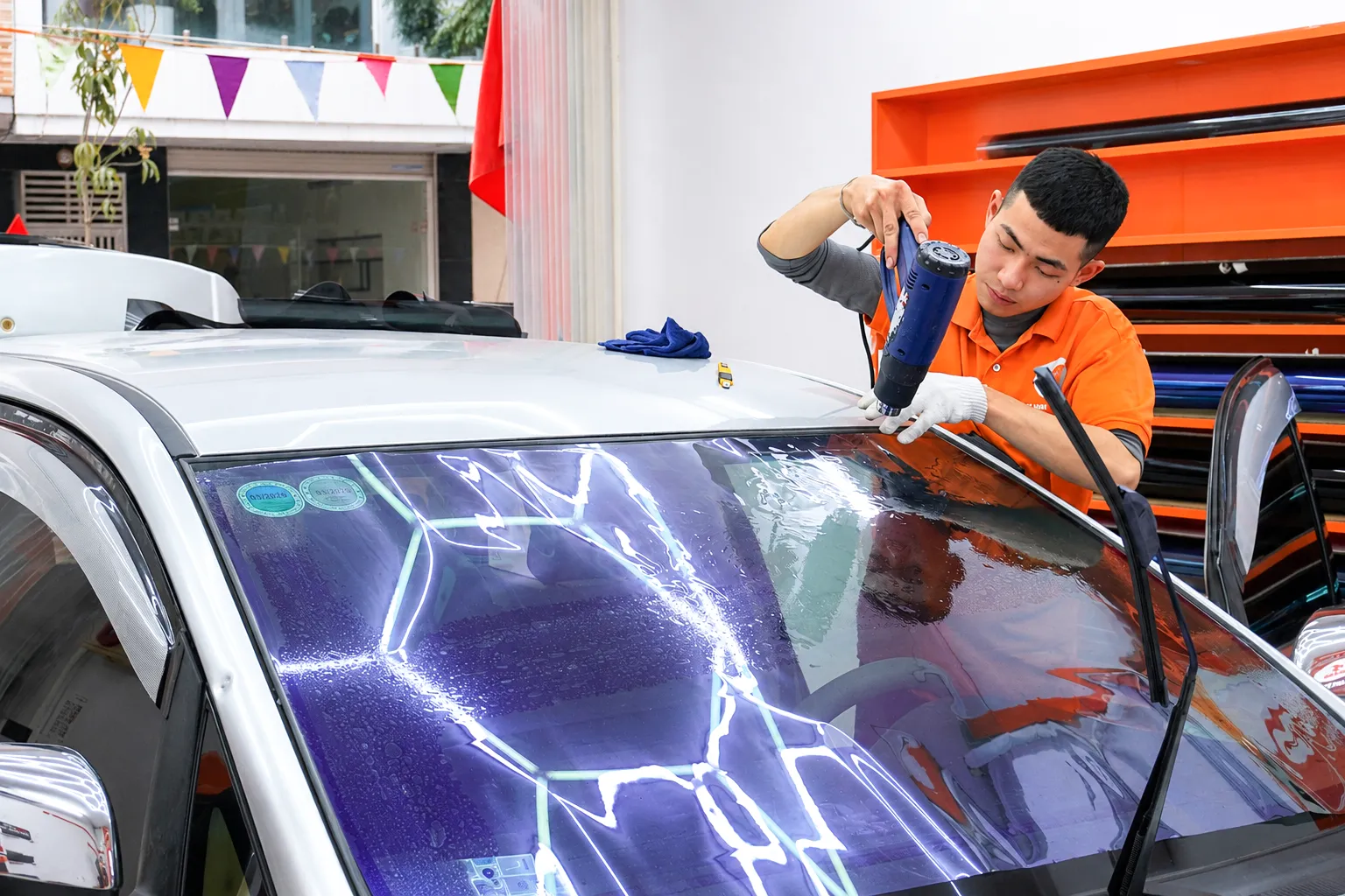 Kỹ thuật viên NND sấy định hình phim cách nhiệt trên kính lái Toyota Innova