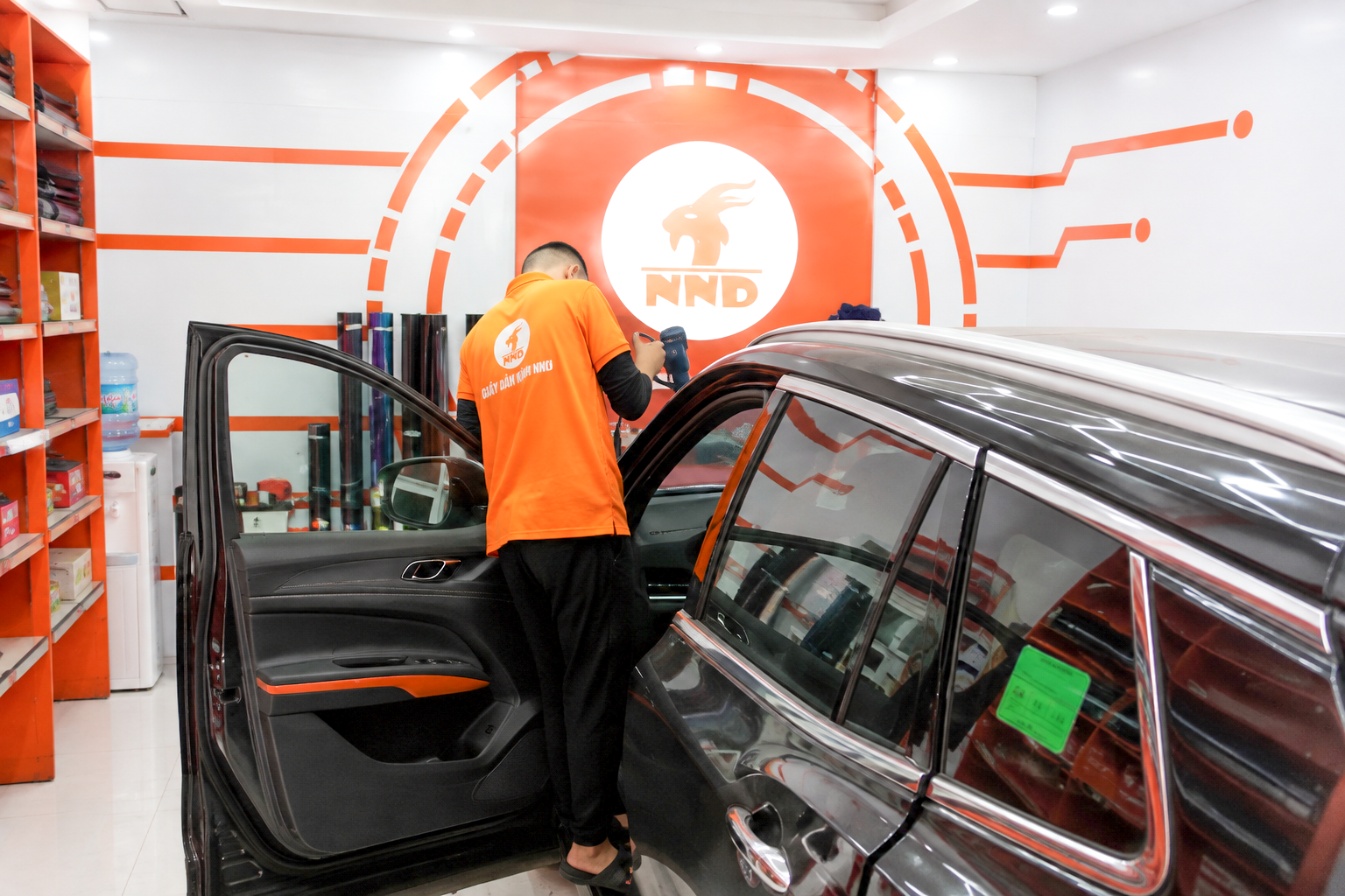 Kỹ thuật viên NND dùng súng nhiệt định hình phim cách nhiệt trên kính sườn ô tô trong quá trình thi công
