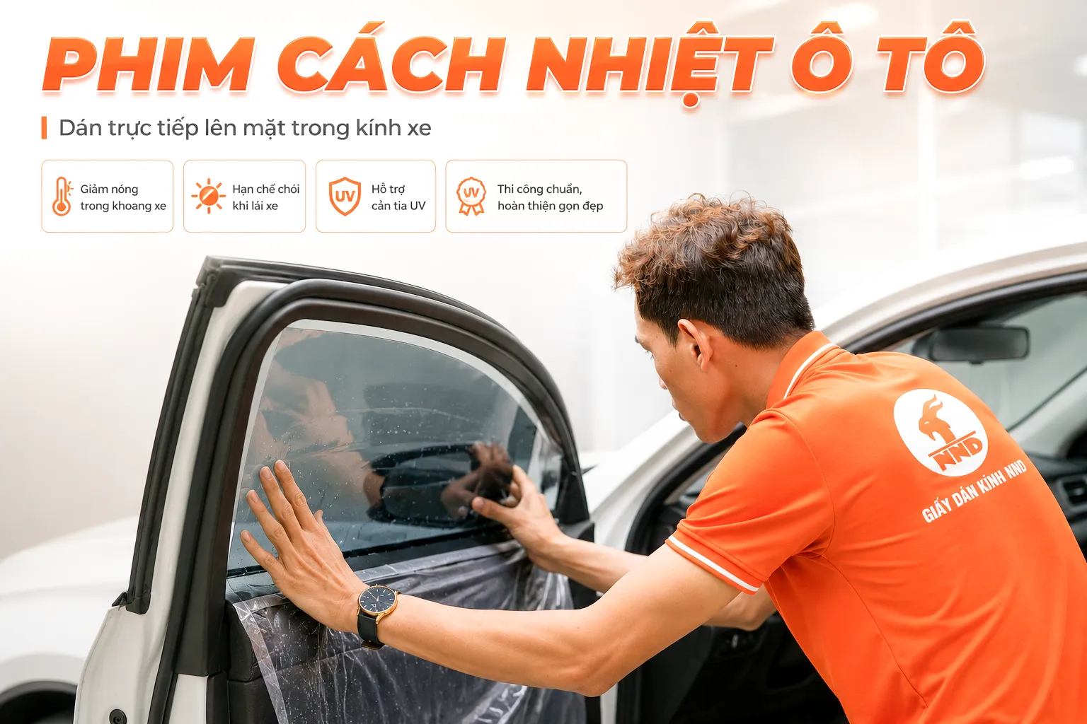 Kỹ thuật viên NND mặc áo cam đang dán phim cách nhiệt trực tiếp lên kính cửa ô tô.