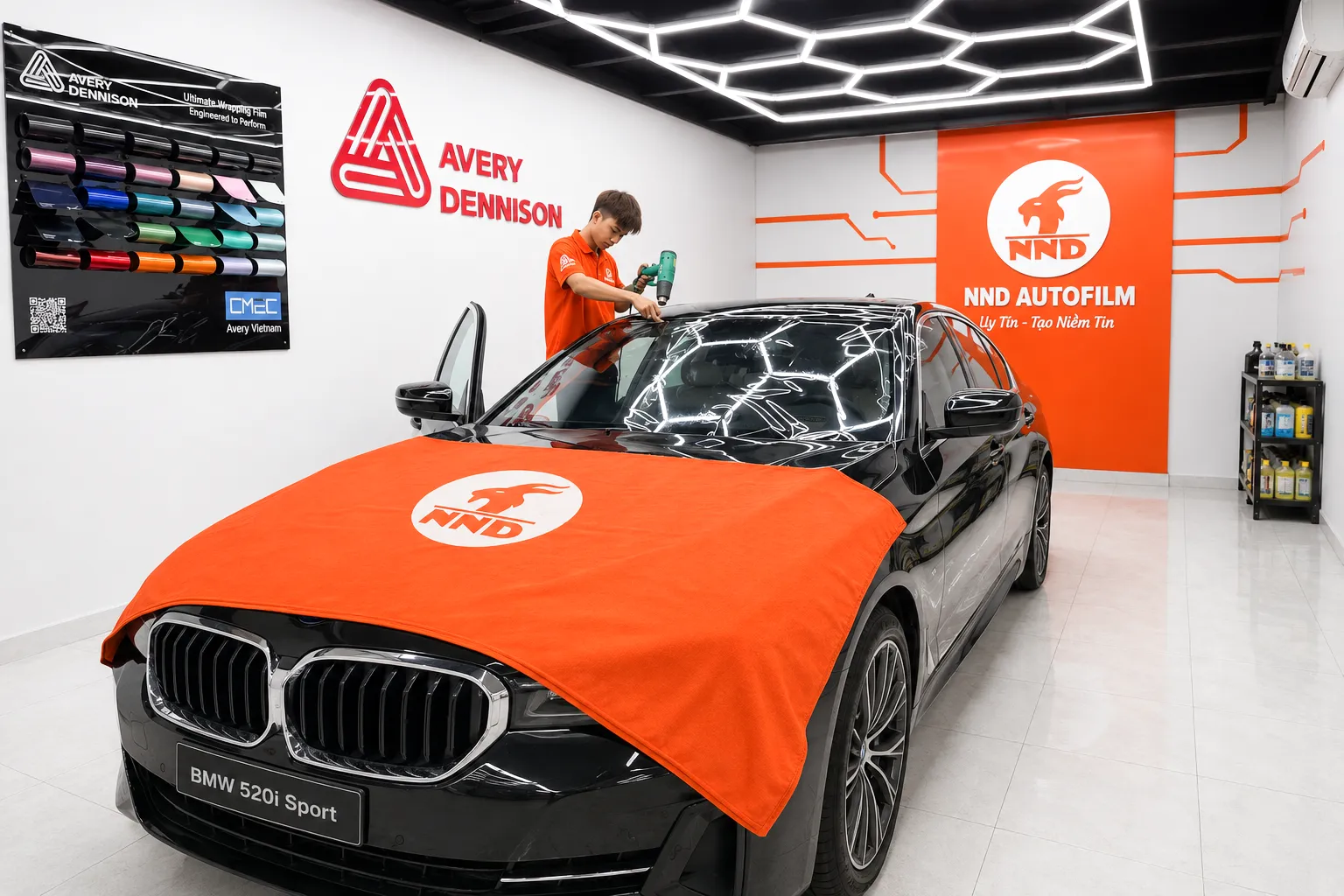 Kỹ thuật viên NND dùng máy khò để sấy phim 3M IR50 trên kính lái BMW 520i Sport