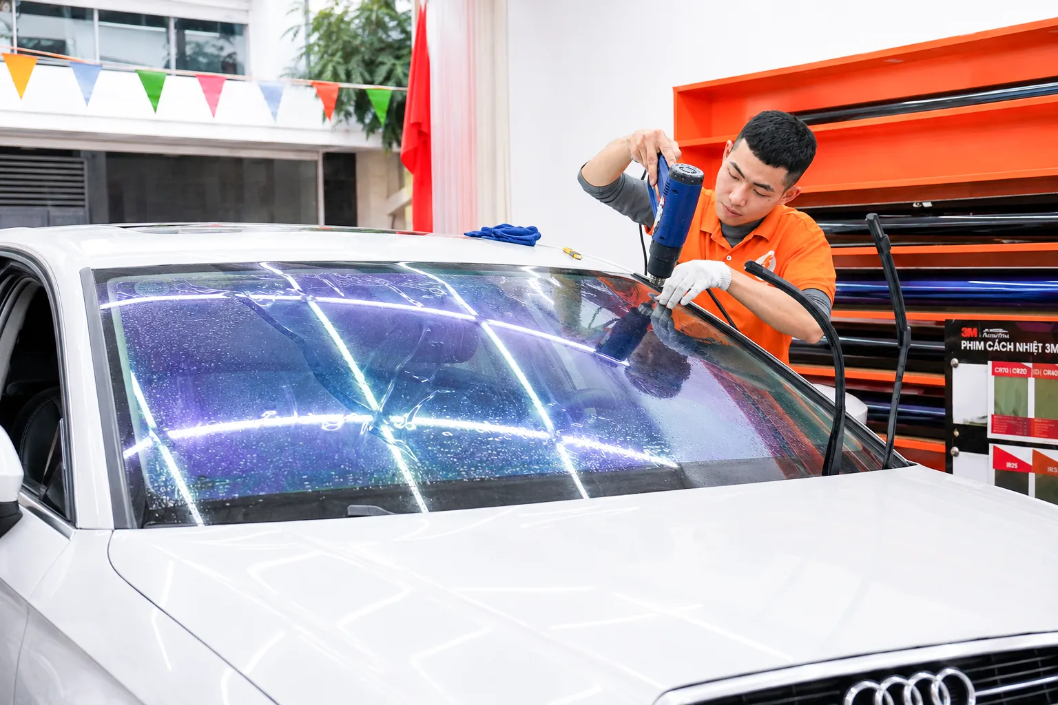Kỹ thuật viên NND dùng máy khò xử lý phim PKL-01 trên kính lái Audi A7