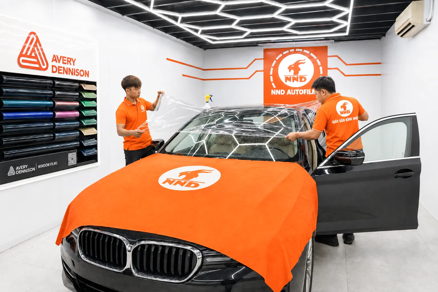 Hai kỹ thuật viên NND căn chỉnh phim cách nhiệt 3M trên kính lái BMW 520i Sport