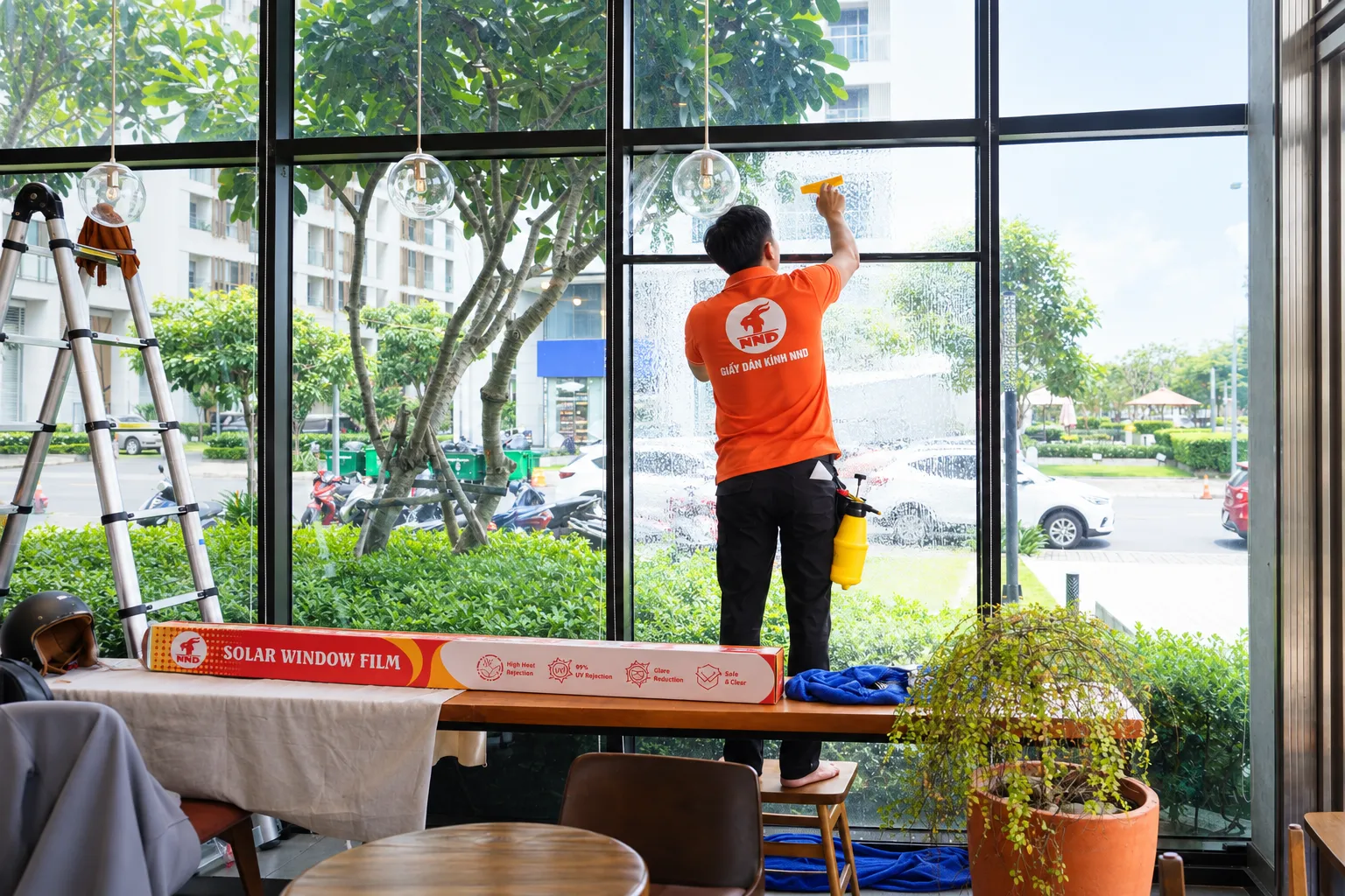 Kỹ thuật viên NND vệ sinh kính cạnh hộp Solar Window Film tại Tropical Forest