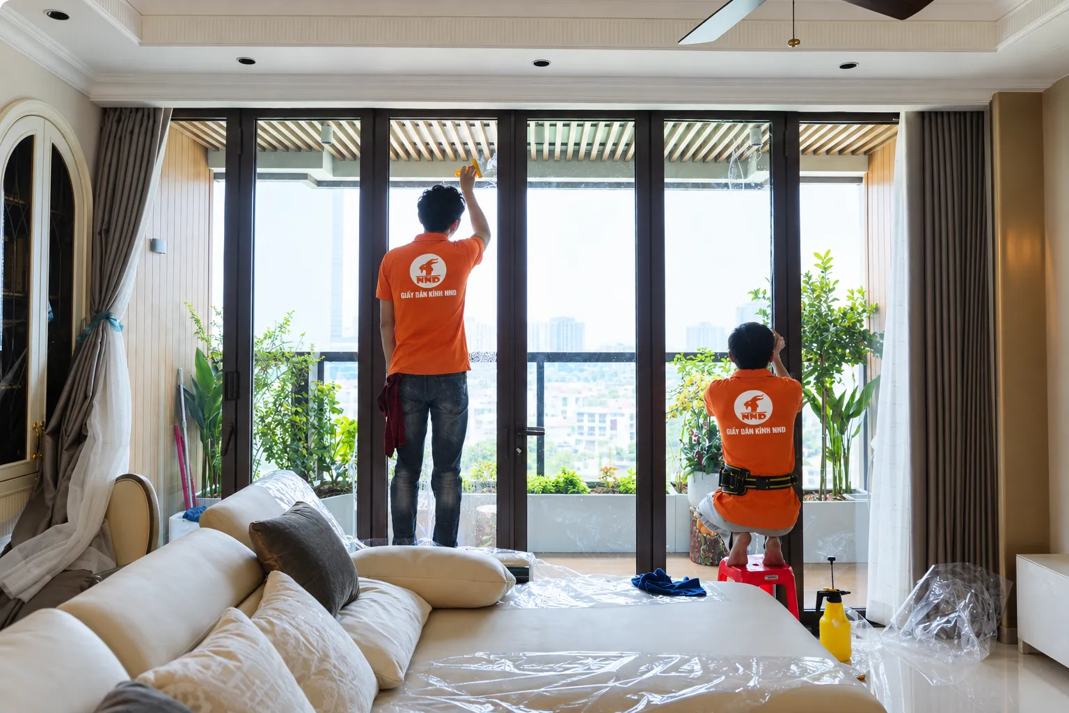 Hai kỹ thuật viên NND thi công phim cách nhiệt trên hệ cửa kính lớn tại biệt thự Vinhomes Ocean Park Gia Lâm