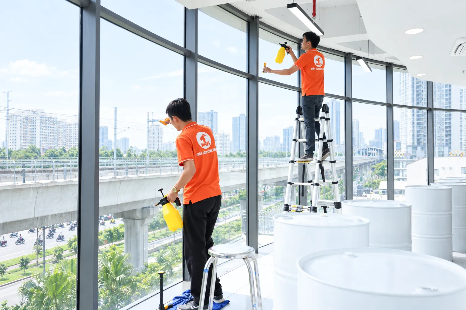 Hai kỹ thuật viên NND vệ sinh bề mặt kính tại tòa nhà Sun Square trước khi dán phim cách nhiệt