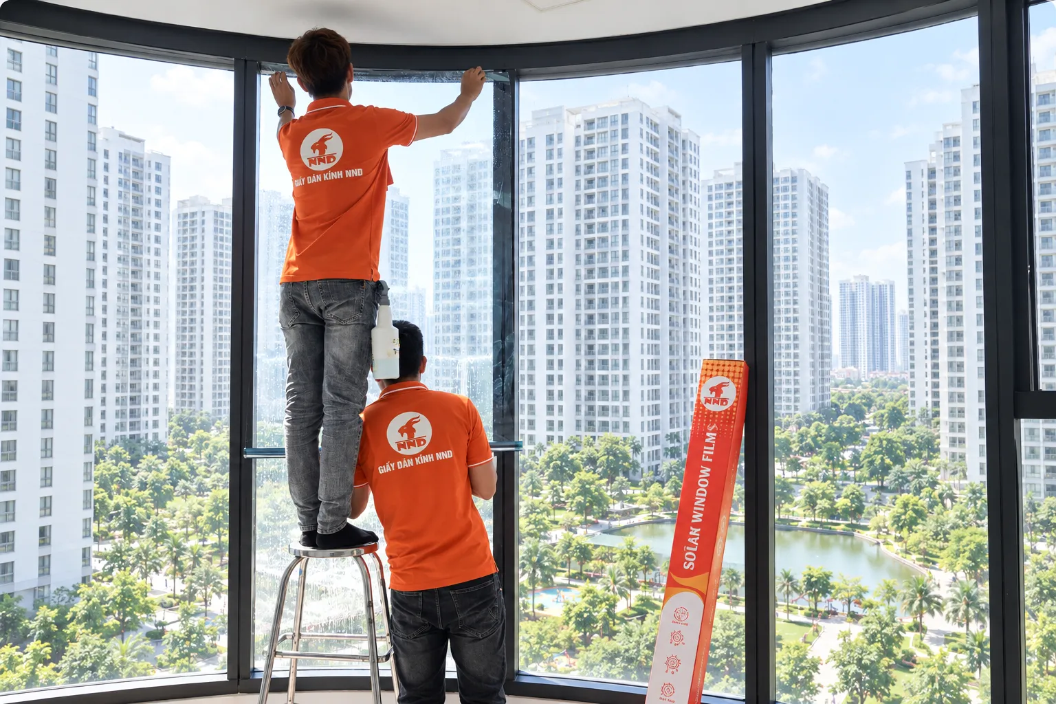 Hai kỹ thuật viên NND thi công phim cách nhiệt theo từng ô kính tại căn hộ Vinhomes Times City