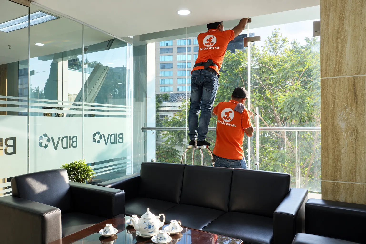 Đội thợ NND xử lý mép phim cách nhiệt trên hệ kính văn phòng BIDV