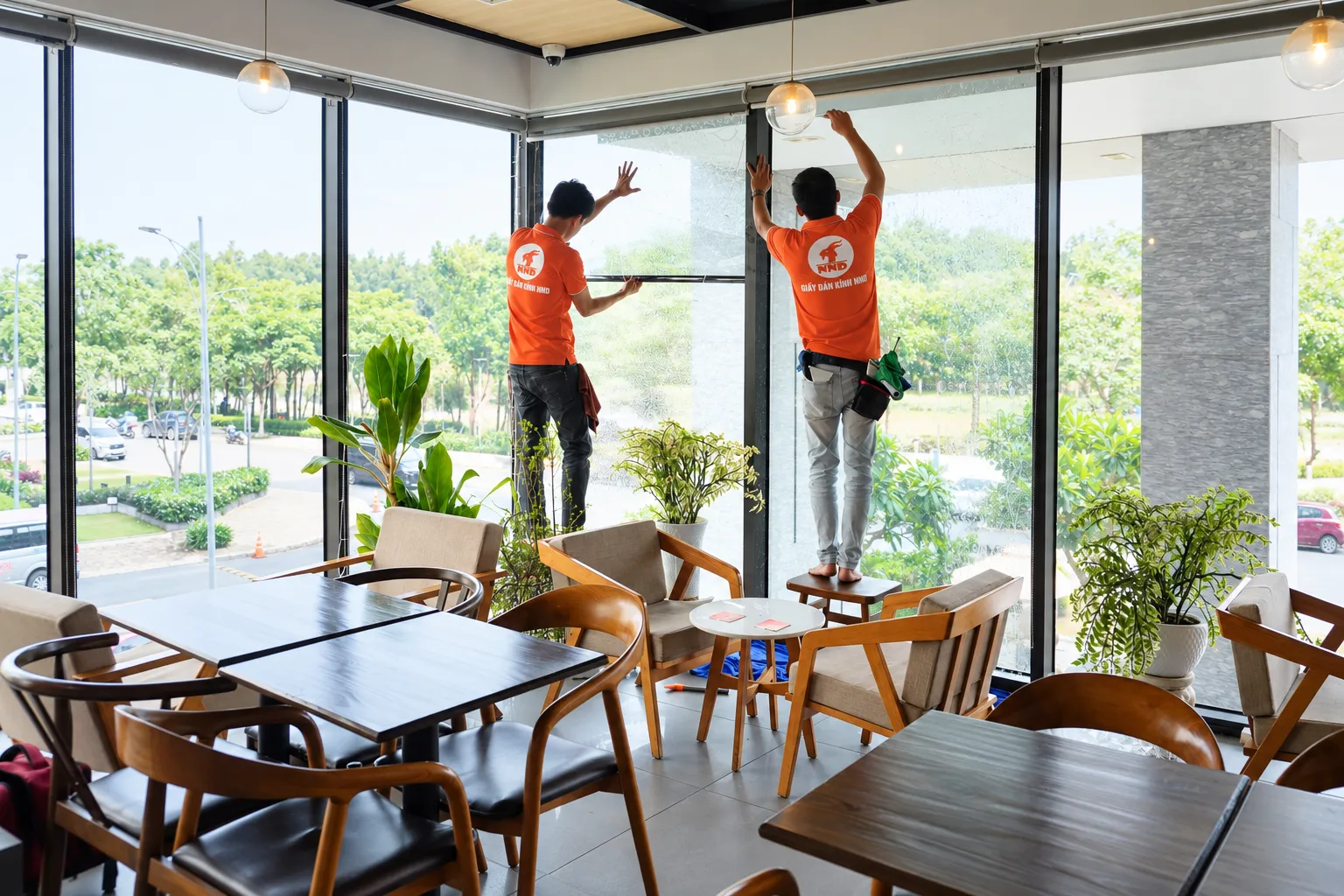 Hai kỹ thuật viên NND căn phim cách nhiệt trên mảng kính lớn tại Tropical Forest