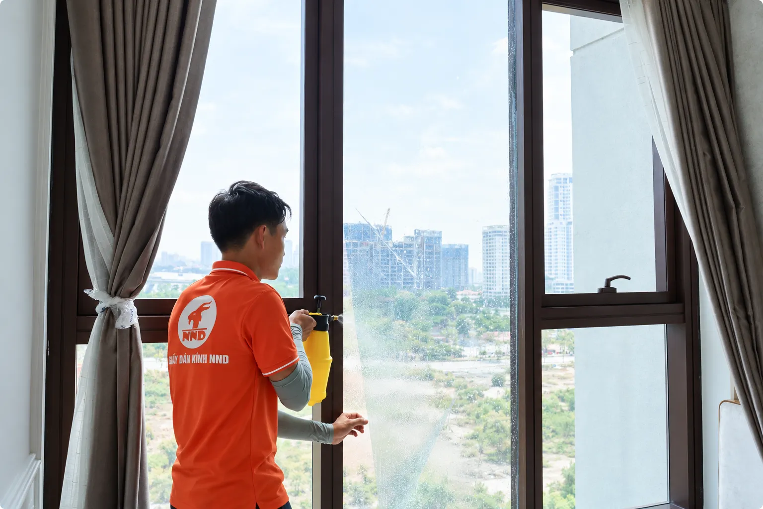 Kỹ thuật viên NND phun dung dịch lên bề mặt kính trước khi dán phim cách nhiệt tại Vinhomes Ocean Park