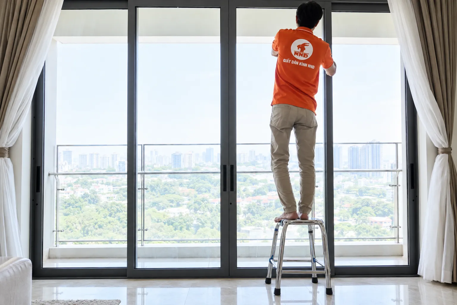 Kỹ thuật viên NND thi công phim cách nhiệt trên hệ kính lớn phòng khách căn hộ Vinhomes Royal City