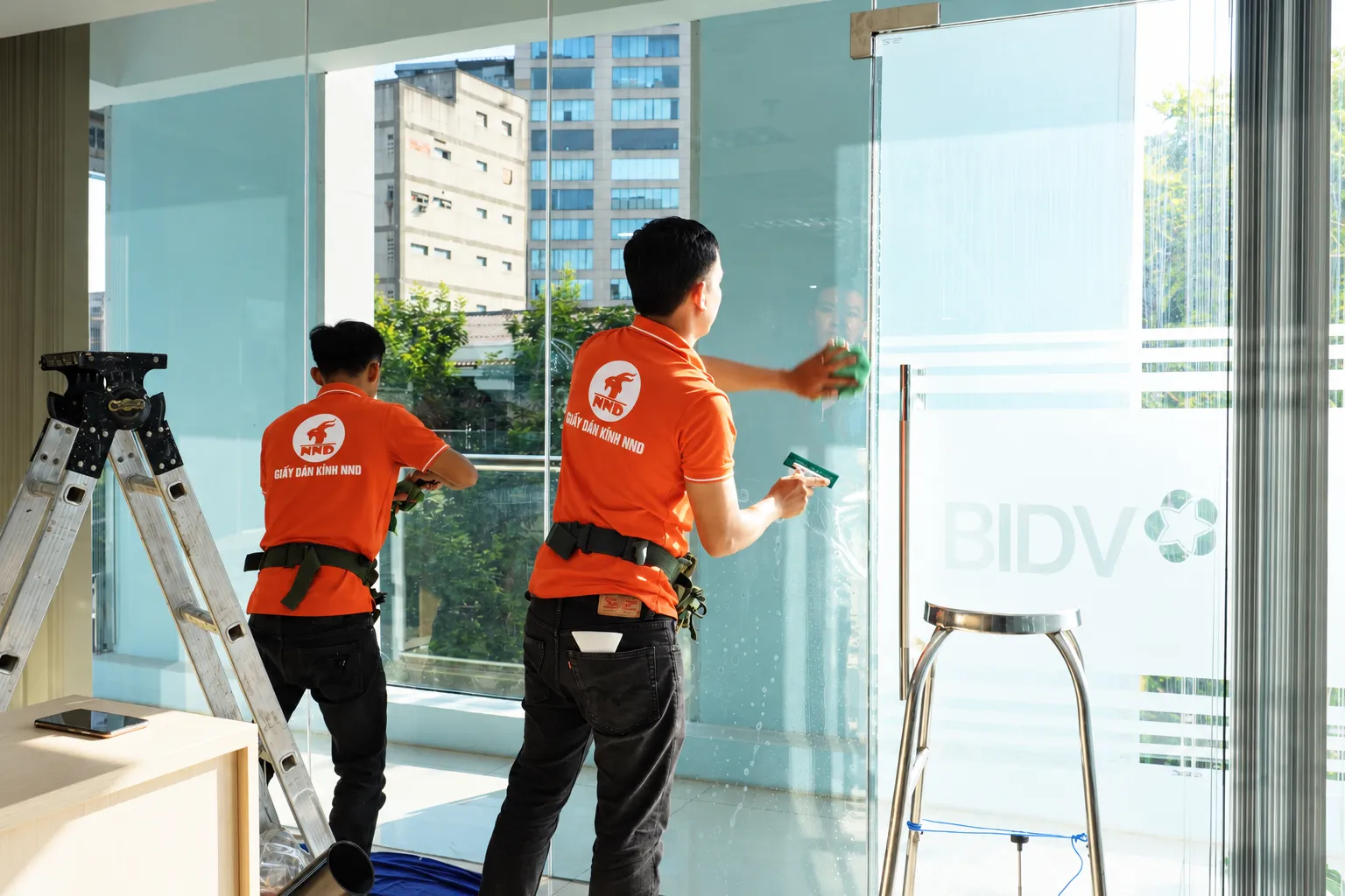 Đội thợ NND hoàn thiện phim cách nhiệt tại khu vực cửa kính văn phòng BIDV