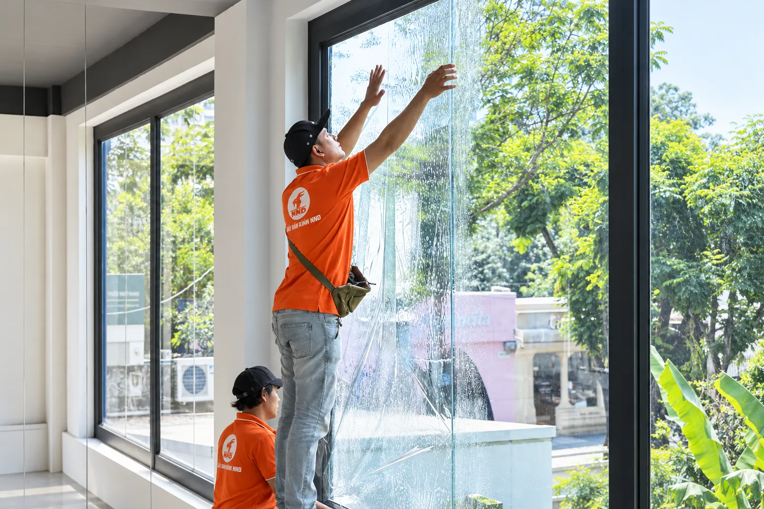 Kỹ thuật viên NND đưa tấm phim cách nhiệt lên mảng kính lớn GS25 CMC Tower