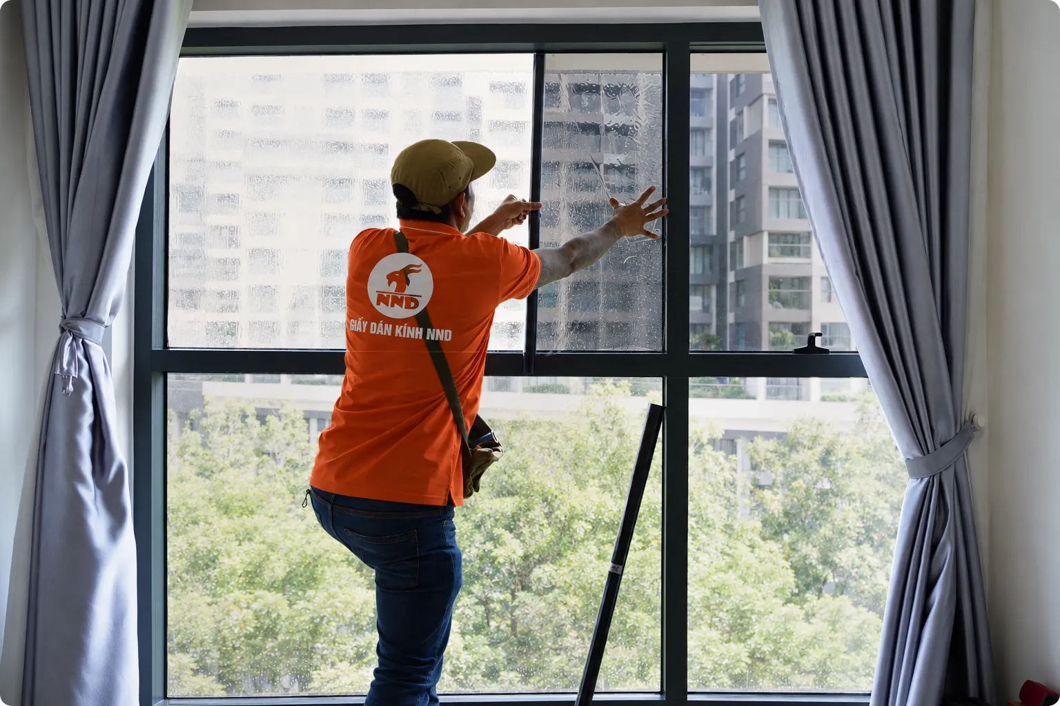 Thợ NND xử lý phim cách nhiệt trên ô kính cửa sổ lớn tại Vinhomes Grand Park