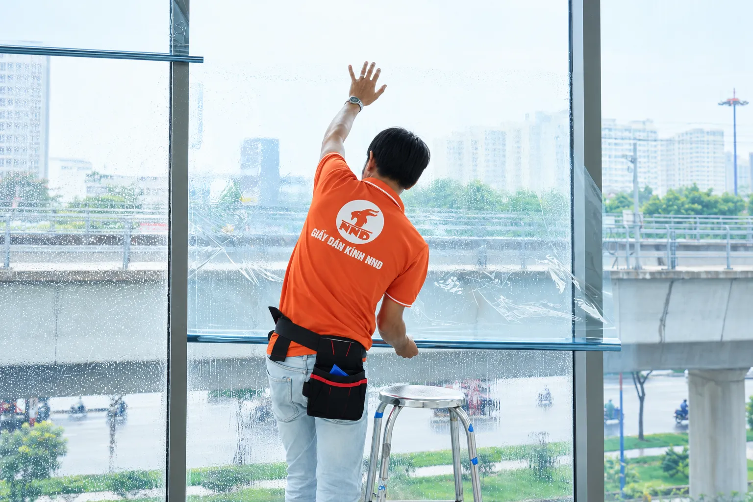 Kỹ thuật viên NND làm phẳng bề mặt phim cách nhiệt trên kính tại Sun Square