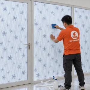Người thợ dùng dụng cụ gạt decal A14 trên vách kính